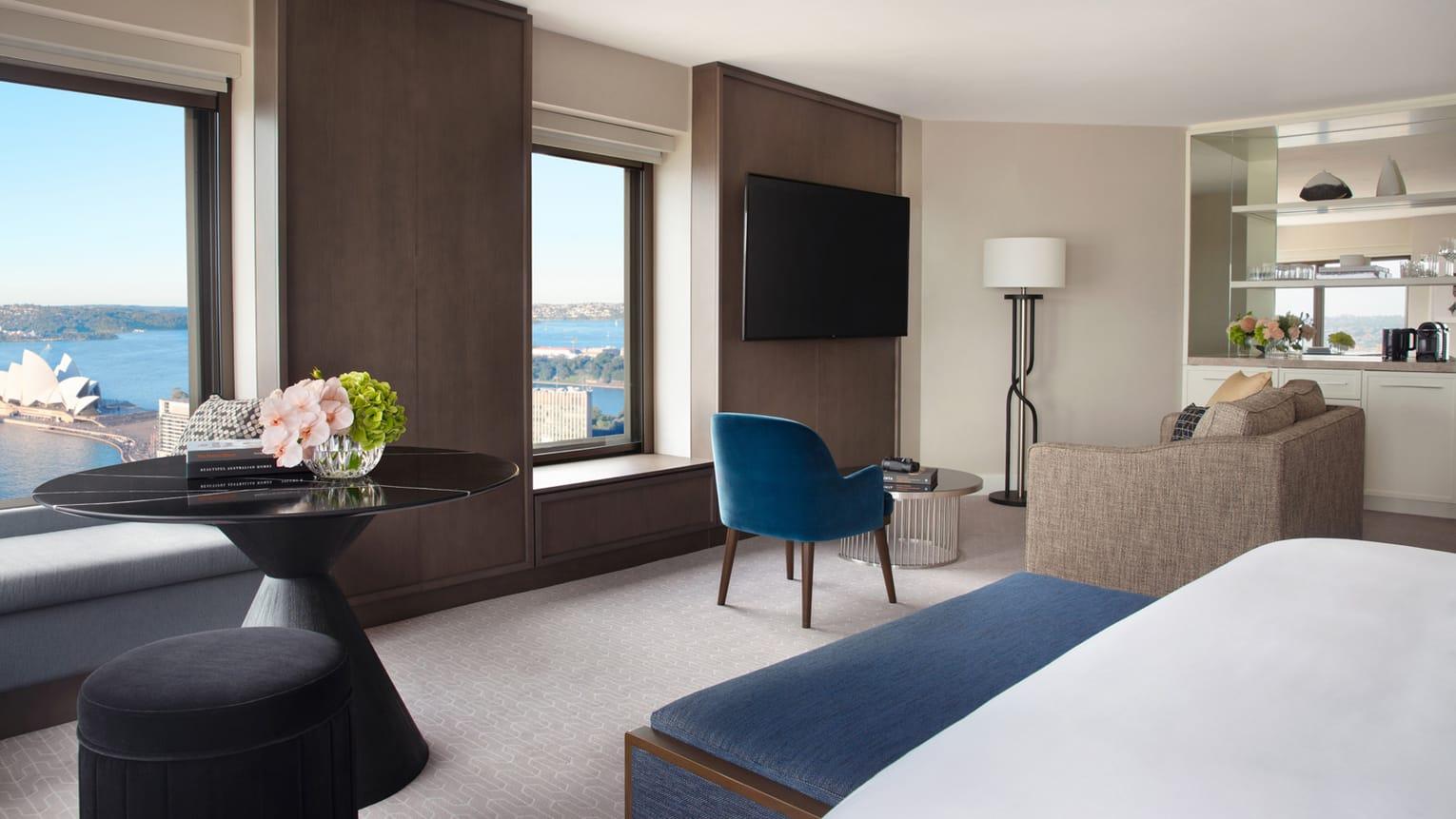 Four Seasons Hotel Сидней Экстерьер фото The photo showcases a modern hotel room with a sleek and contemporary design. It features a large window that offers a view of the outside. The room includes:

- A comfortable seating area with a blue chair and a light-colored sofa.
- A round black t